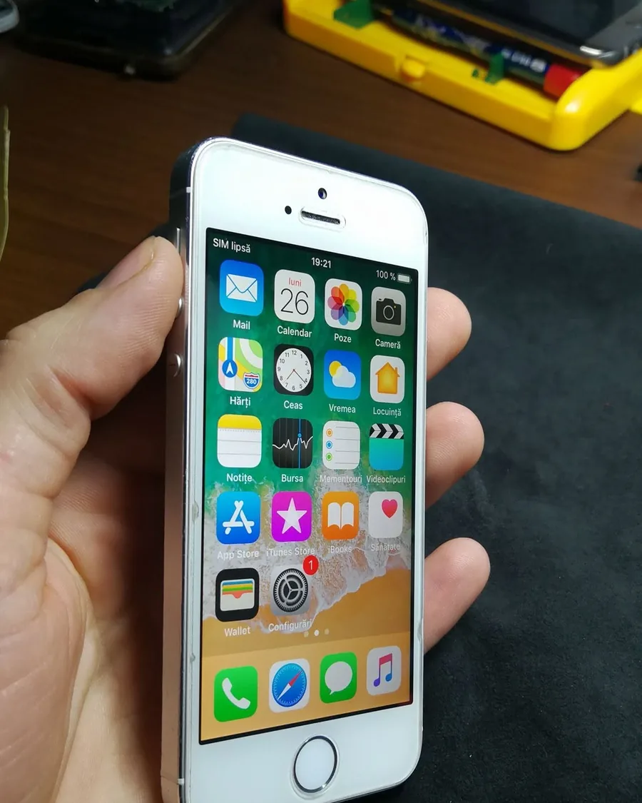 Un iPhone reparat, ținut în mână deasupra bancului de lucru